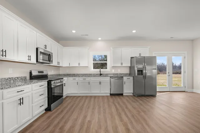 a kitchen with a refrigerator a stove top oven a sink dishwasher and wooden floor