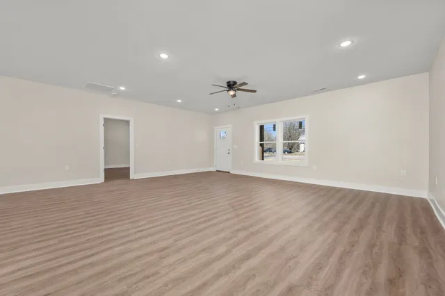 a view of an empty room with a window and wooden floor