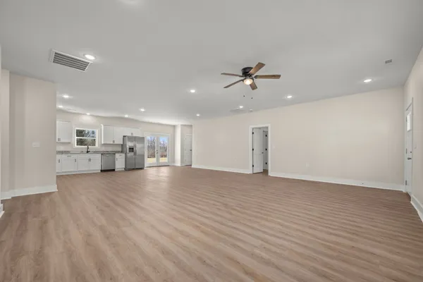 a view of empty room with wooden floor and ceiling fan