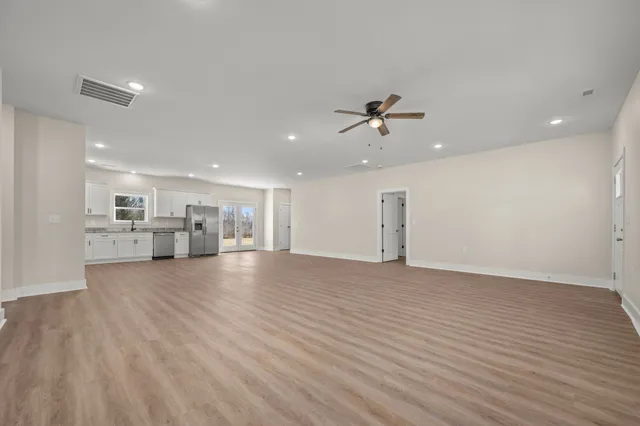 a view of empty room with wooden floor and ceiling fan