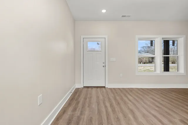 an empty room with wooden floor and windows
