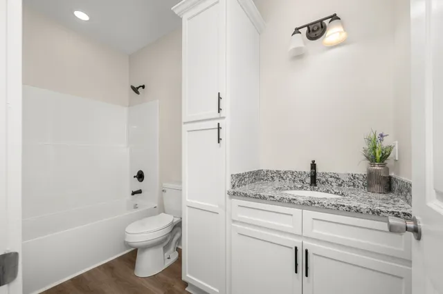 a bathroom with a granite countertop sink a toilet and shower