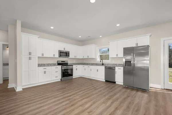 a large kitchen with cabinets wooden floor stainless steel appliances and a window