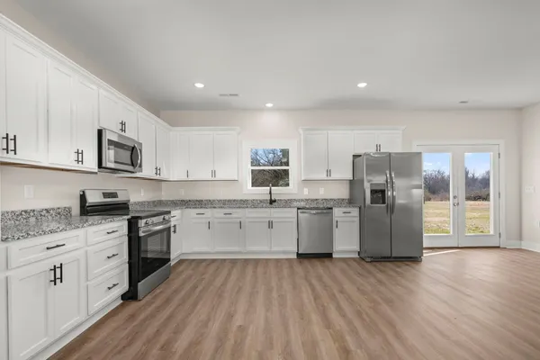 a kitchen with a refrigerator a stove top oven a sink dishwasher and wooden floor
