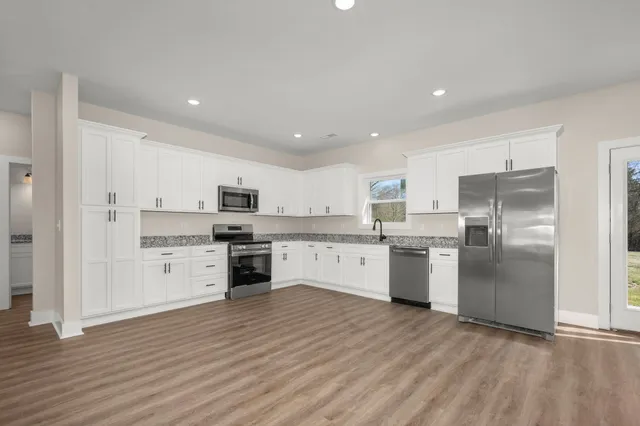 a large kitchen with cabinets wooden floor stainless steel appliances and a window