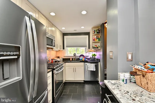 a kitchen with stainless steel appliances granite countertop a refrigerator a stove and a sink