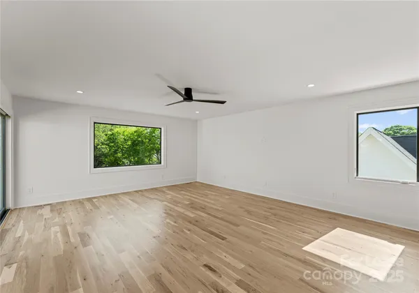 a view of an empty room with a window and a kitchen