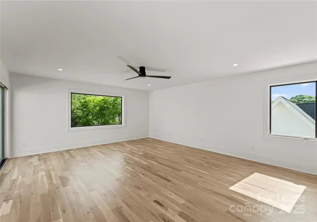 a view of an empty room with a window and a kitchen