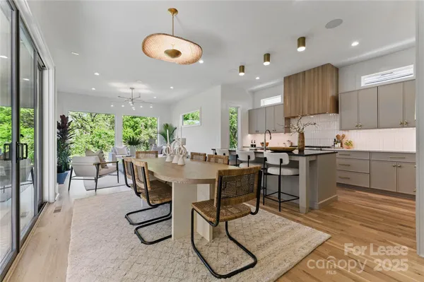 a kitchen with stainless steel appliances granite countertop a stove top oven a sink dishwasher a dining table and chairs with wooden floor