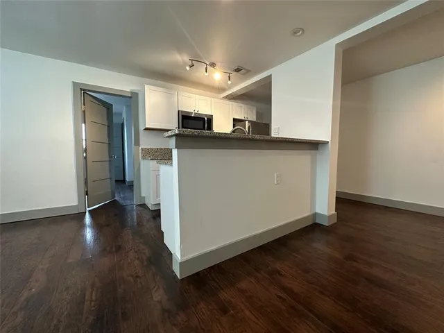 a view of a hallway with wooden floor and a kitchen