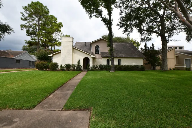 a front view of a house with a yard and trees