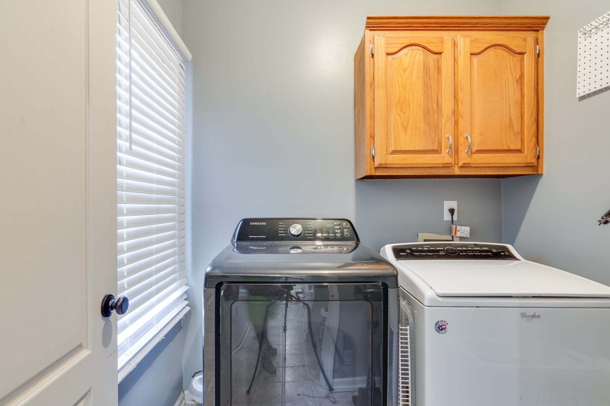 779 Early Earner Cove Collierville, TN 38017 - Photo 12 of 29 Functional laundry area featuring light gray walls, a window with horizontal blinds, and natural wood cabinetry with curved panel doors