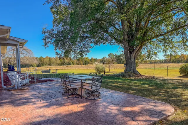 a view of a backyard with table and chairs under a large tree
