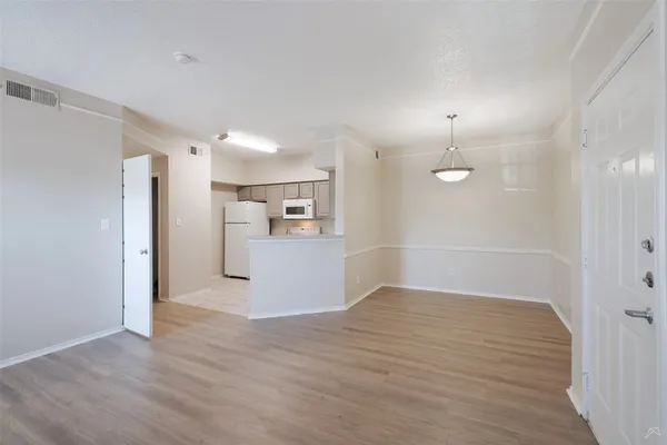 a view of a room with wooden floor and kitchen view