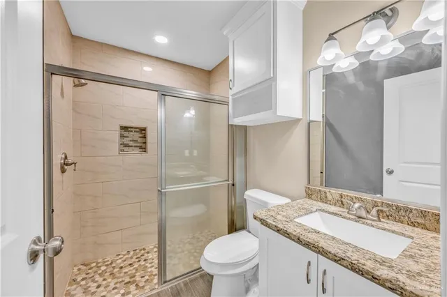 a bathroom with a granite countertop sink toilet and shower