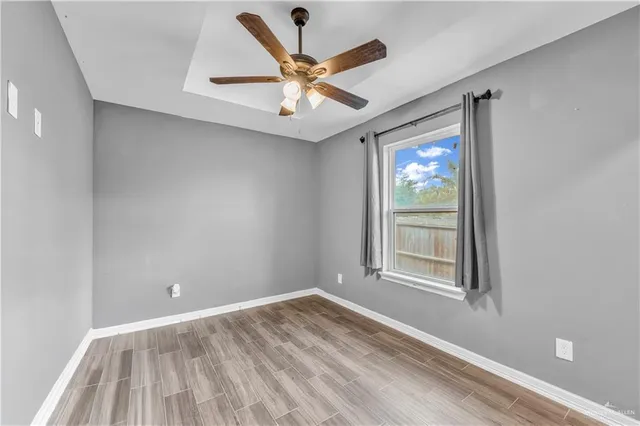 an empty room with wooden floor and ceiling fan