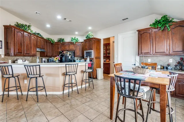 a kitchen with stainless steel appliances kitchen island granite countertop a table chairs and a refrigerator