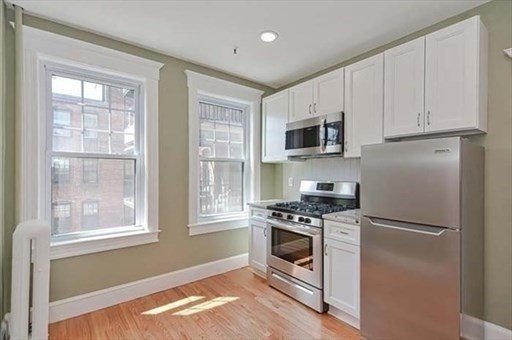 70 Strathmore Road, Unit 9B Boston, MA 02135 - Photo 5 of 19 a kitchen with cabinets stainless steel appliances a sink and a window