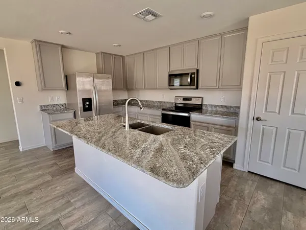 a kitchen with stainless steel appliances granite countertop a sink stove microwave and refrigerator