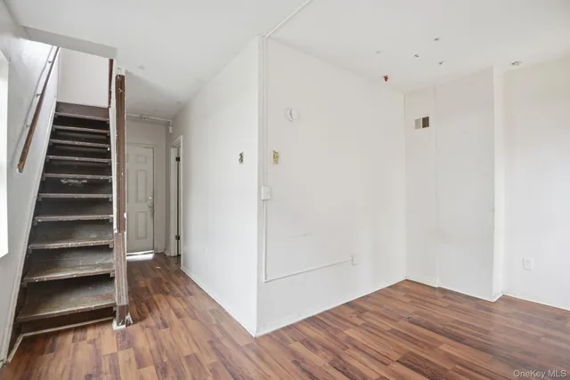 a view of an empty room with wooden floor and stairs