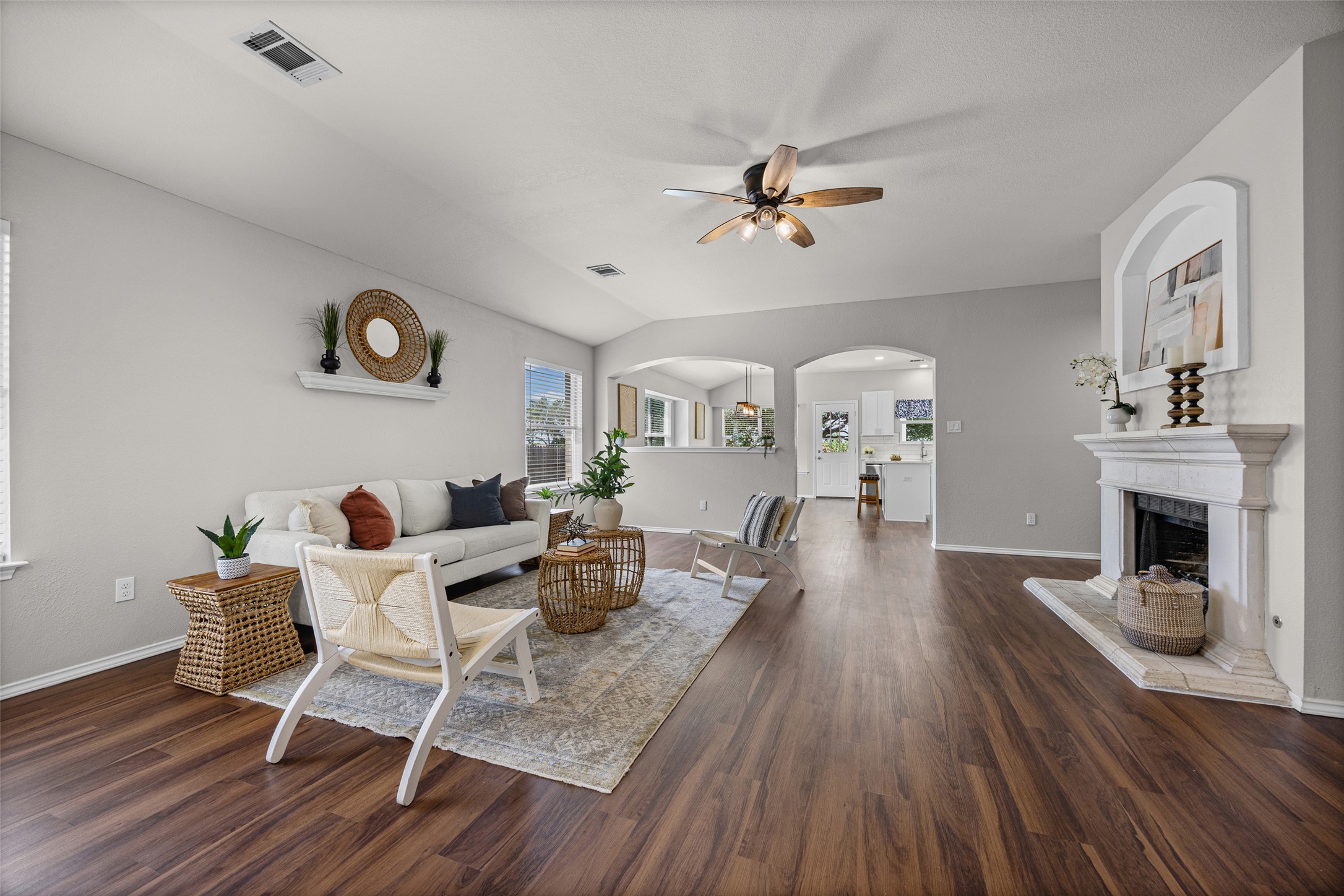 1524 Lochaline Loop Pflugerville, TX 78660 - Photo 6 of 22 Rich hardwood flooring flows through this bright living area, anchored by a classic fireplace and a vaulted ceiling with a fan.