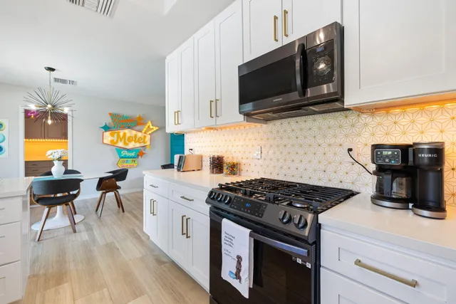 a kitchen with stainless steel appliances a stove a microwave a sink and cabinets