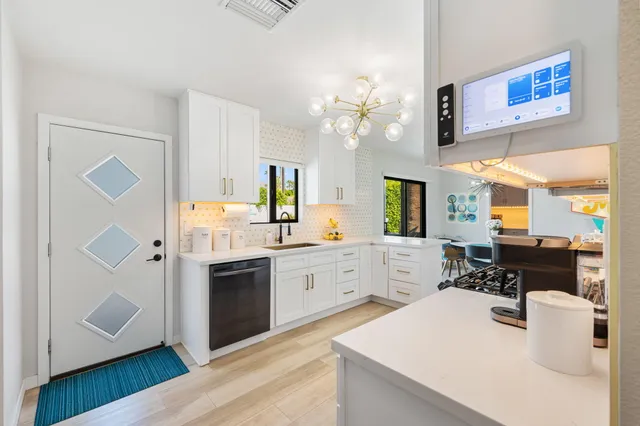 a large kitchen with a refrigerator a stove a sink dishwasher a dining table and chairs with wooden floor