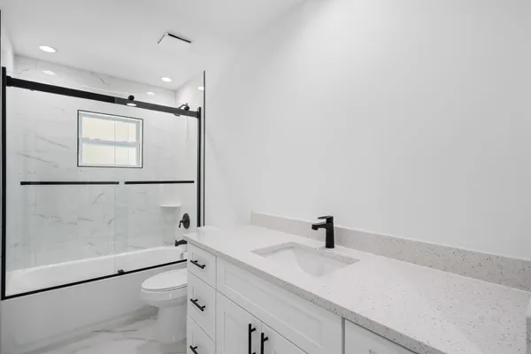 a bathroom with a sink a toilet and shower