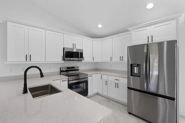 a kitchen with granite countertop a refrigerator and a stove top oven