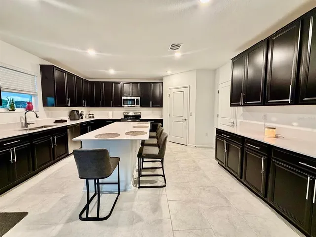 a large kitchen with kitchen island granite countertop a stove a sink a dining table and chairs