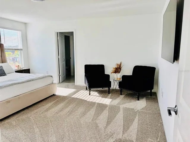 a bedroom with a bed chairs and a window