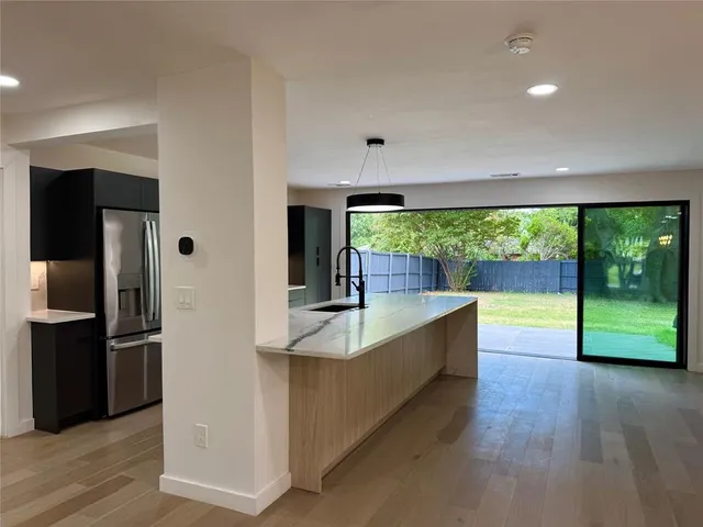a kitchen with stainless steel appliances granite countertop a refrigerator and a wooden floor