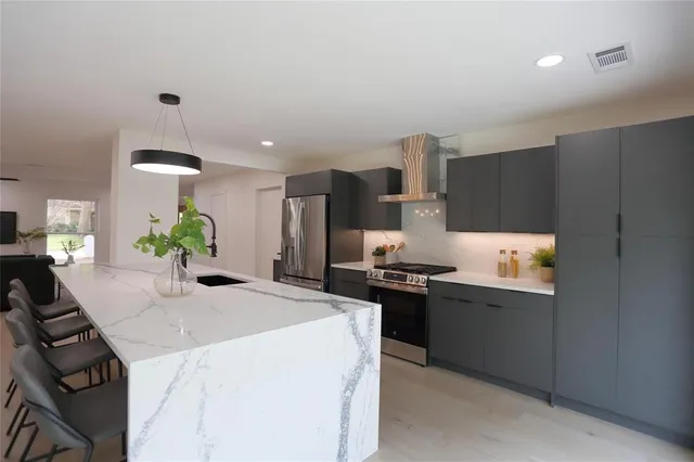 a kitchen with stainless steel appliances a stove a refrigerator a sink a stove and white cabinets