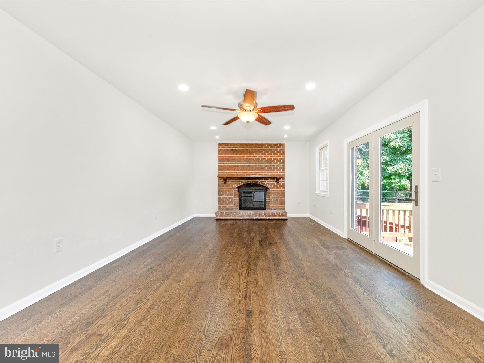 8395 Buckeye Court Frederick, MD 21702 - Photo 16 of 56 an empty room with wooden floor a fireplace and windows