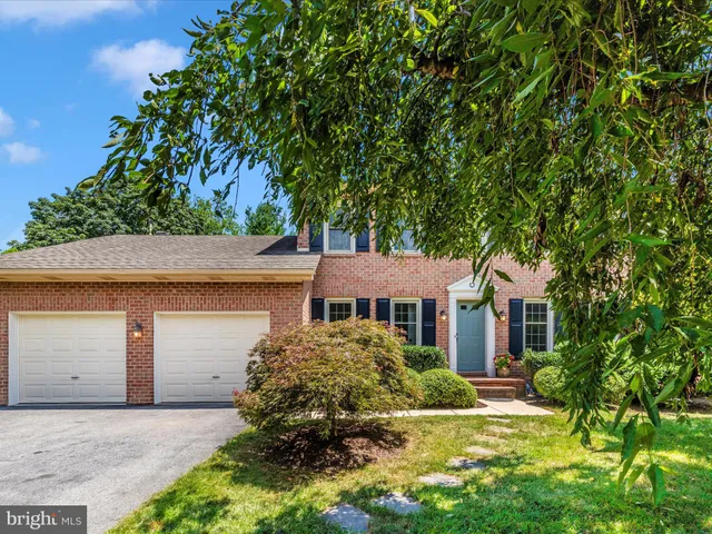a view of a swimming pool with lawn chairs and large trees