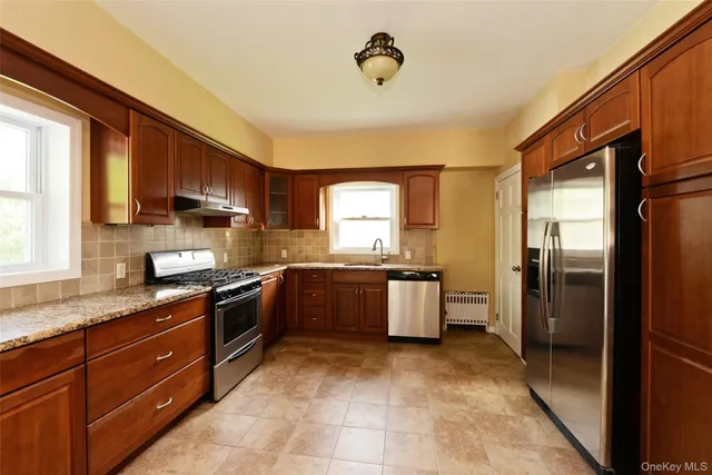 a kitchen with stainless steel appliances granite countertop a refrigerator a sink dishwasher stove and oven