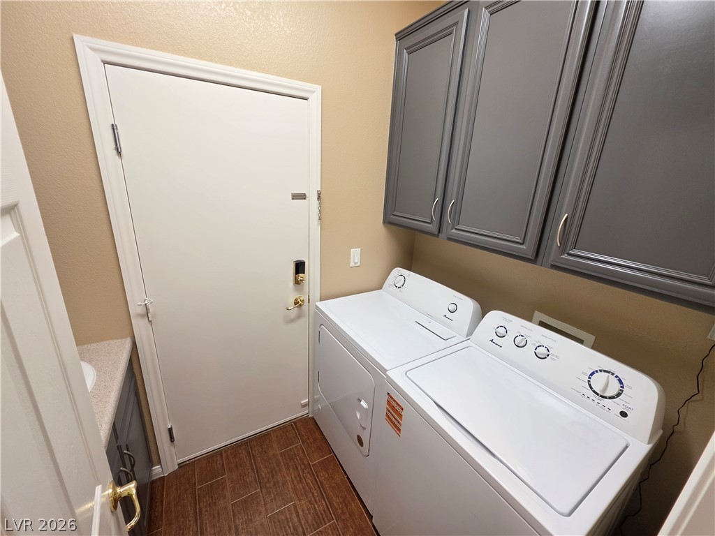 209 Opera House Street Henderson, NV 89012 - Photo 23 of 45 A functional laundry space matches rich wood-look flooring with deep grey overhead cabinetry.