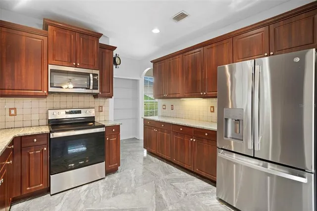 a kitchen with granite countertop a refrigerator stove and microwave