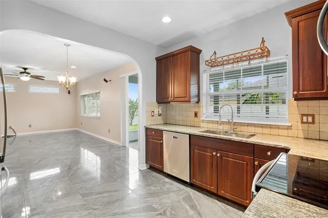 a large kitchen with granite countertop a sink and dishwasher a stove top oven with wooden floor