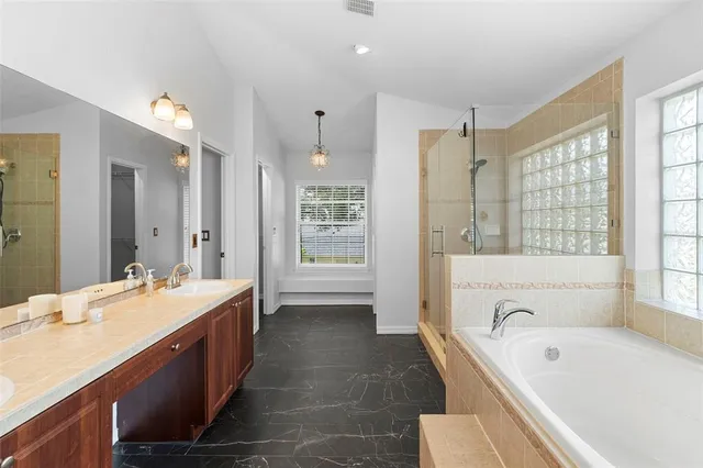 a spacious bathroom with a tub sink shower and mirror