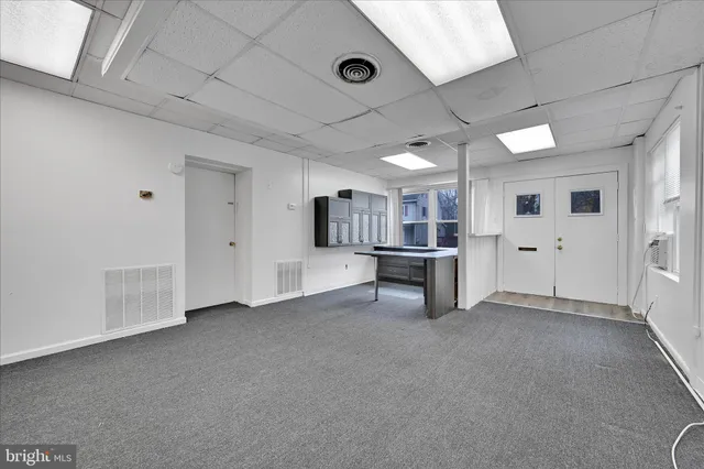 a view of an empty room with kitchen and window