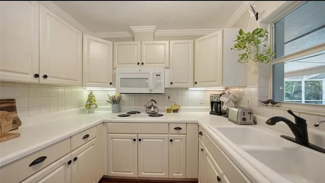 a kitchen with white cabinets white appliances and sink
