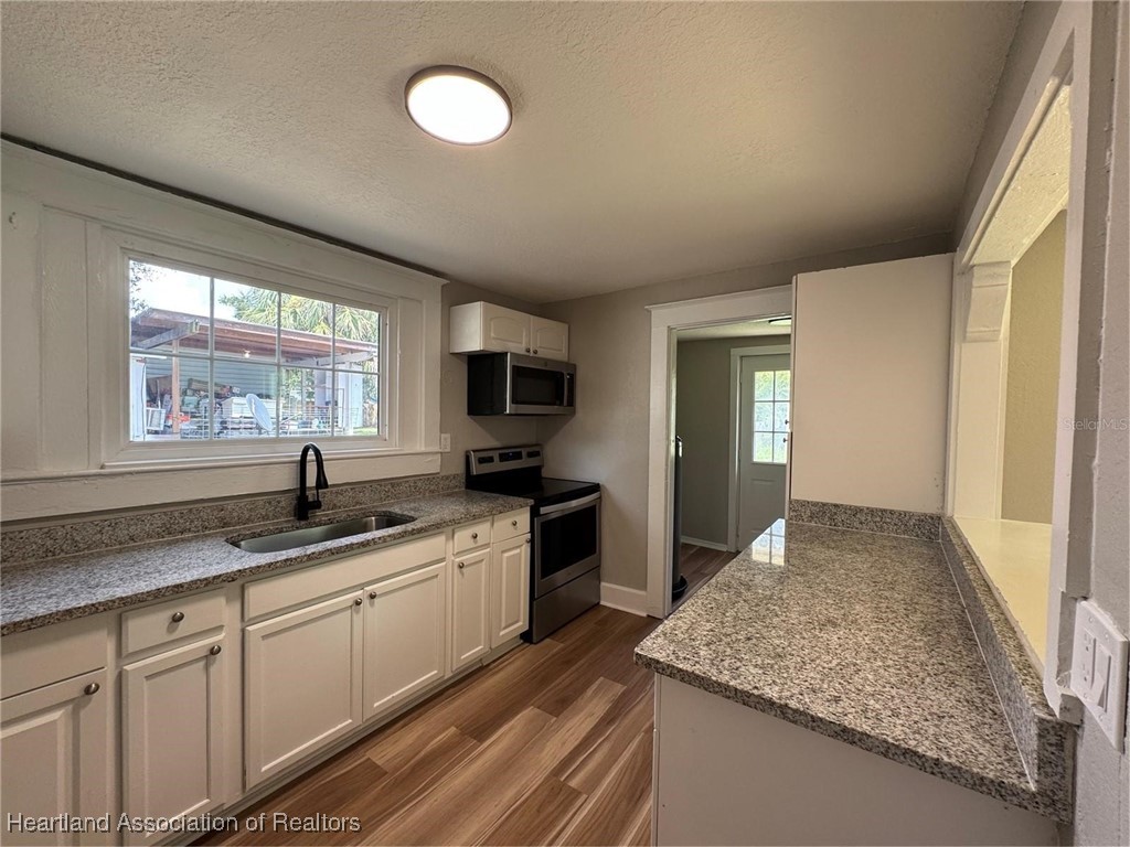 111 D Street Frostproof, FL 33843 - Photo 16 of 40 a kitchen with granite countertop kitchen island white cabinets and stainless steel appliances