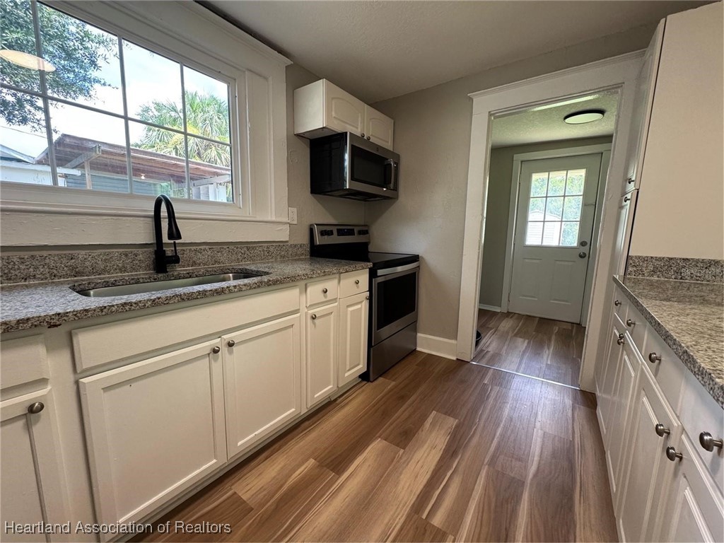 111 D Street Frostproof, FL 33843 - Photo 19 of 40 a kitchen with granite countertop stainless steel appliances a stove sink and wooden floor