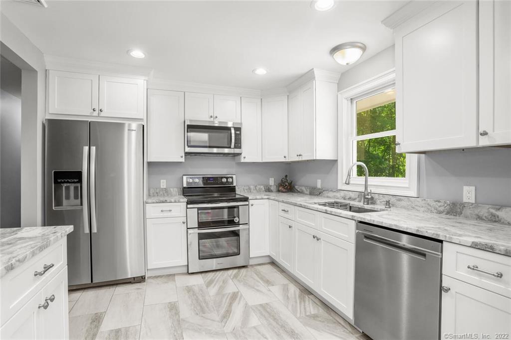 a kitchen with stainless steel appliances granite countertop a stove a sink and a refrigerator