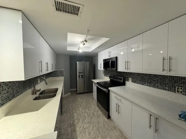 a kitchen with stainless steel appliances granite countertop a sink a stove and a refrigerator