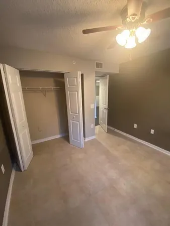 an empty room with closet and a chandelier fan