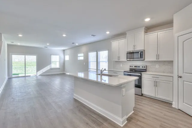 a large kitchen with stainless steel appliances granite countertop a stove a sink dishwasher and a oven with white cabinets