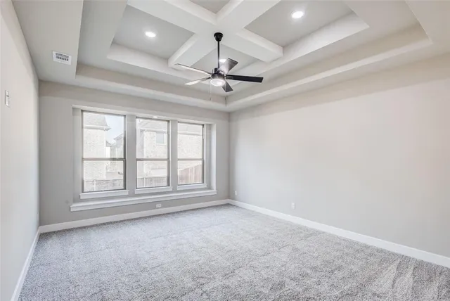 an empty room with chandelier fan and windows
