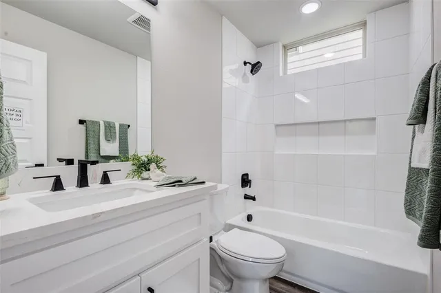 a bathroom with a bathtub shower sink vanity mirror and toilet